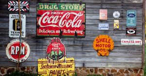 Collection of vintage advertising signs on rustic wooden wall showcasing classic brands.